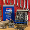 19-piece Bad Dog multipurpose drill bit set in open blue case displayed on workbench with retail packaging and brake rotor in background