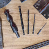 Various multipurpose drill bits on a wooden surface with metal hardware pieces