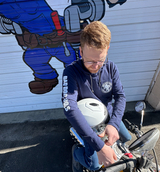 Man in navy hoodie prepping motorcycle near garage mural Man in navy hoodie prepping motorcycle near garage mural