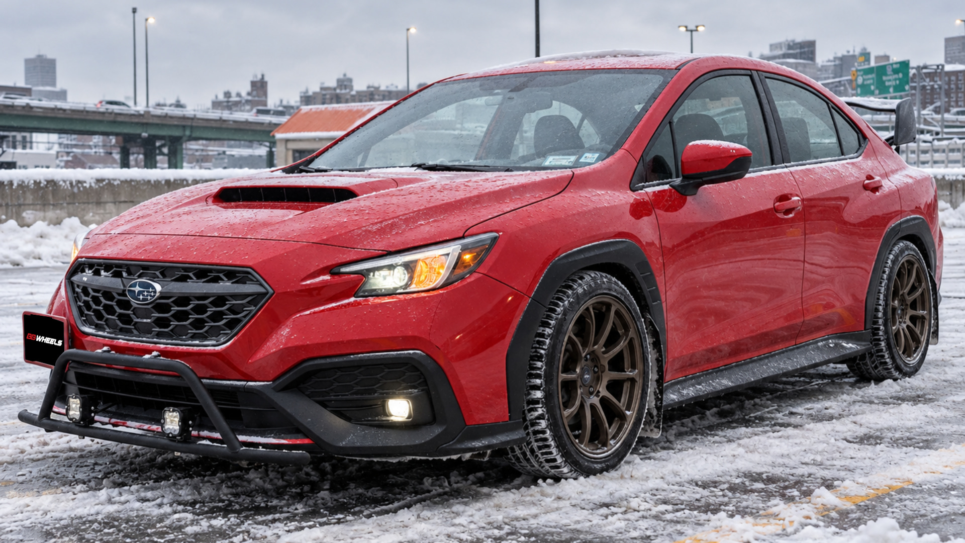 Red Subaru with aftermarket wheels parked in a snowy parking area.
