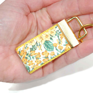 gold and yellow floral keychain in hand mini version gold and yellow floral keychain in hand mini version