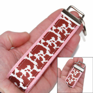 brown cow spot keychain silver hardware in both wristlet and mini size shown in hand brown cow spot keychain silver hardware in both wristlet and mini size shown in hand