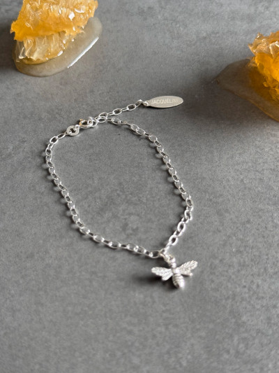 Sterling silver bee bracelet with a personalised silver tag. The bracelet is shown with honeycomb in the background. Sterling silver bee bracelet with a personalised silver tag. The bracelet is shown with honeycomb in the background.