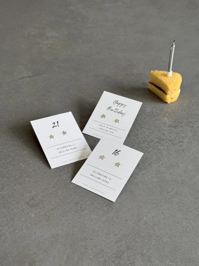 Sterling silver star earrings on birthday milestone message cards.