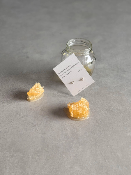 Silver bee earring on a message card with an original 'She is a queen' Haiku poem. The earrings are shown with an open pot of honey and some honeycomb.