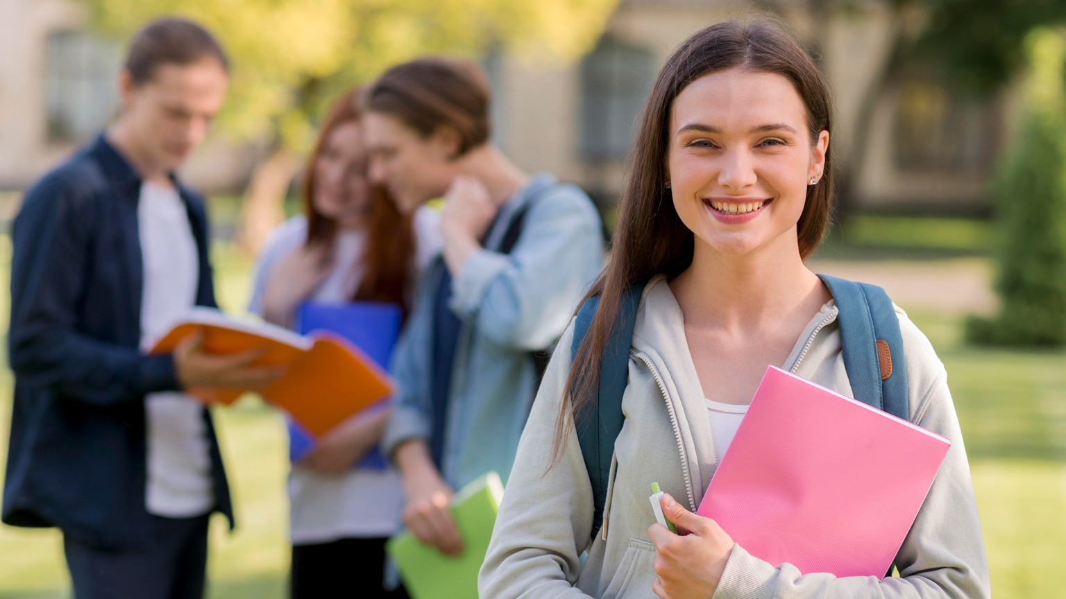 Smiling teenager holding pink notebook