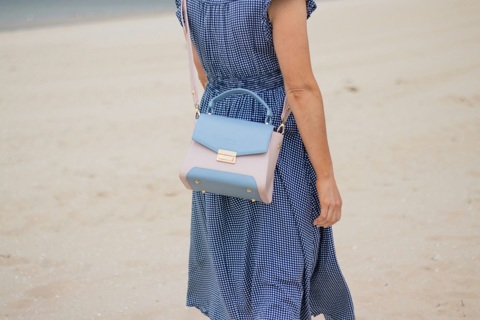 A woman in a blue dress carrying a blue and white crossbody bag