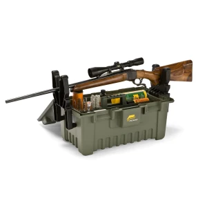 Plano green hunting storage and cleaning box with an integrated gun rest, shown holding a scoped rifle and various cleaning supplies including brushes, oils, and tools. The sturdy plastic case features built-in clamps to secure the firearm for maintenance.