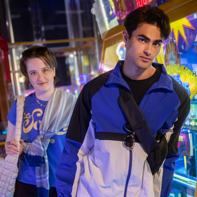 Two people standing in an arcade with illuminated game machines behind them.