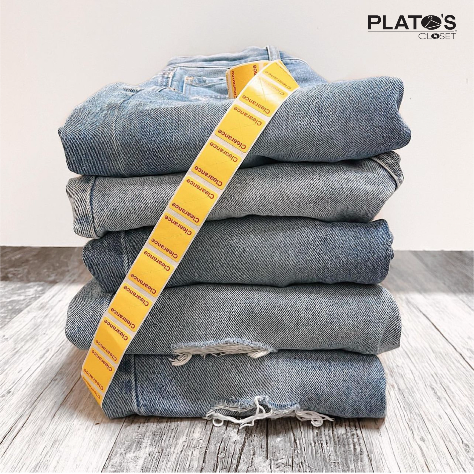 A folded stack of jeans with a roll of clearance tags on top of them