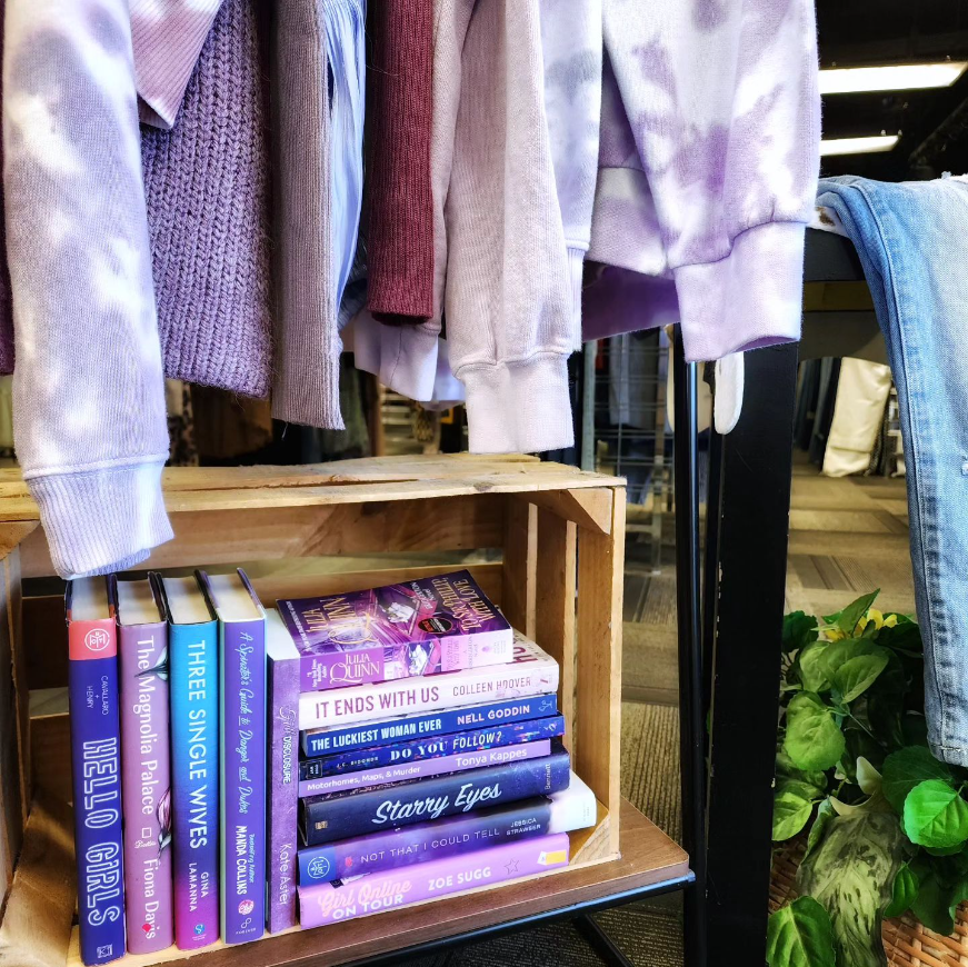 Books displayed on a rack with purple sweaters.