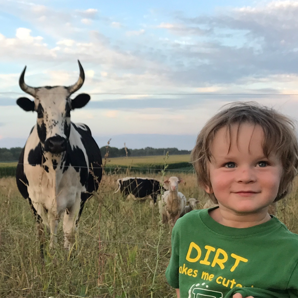 Child smiling with cows in field