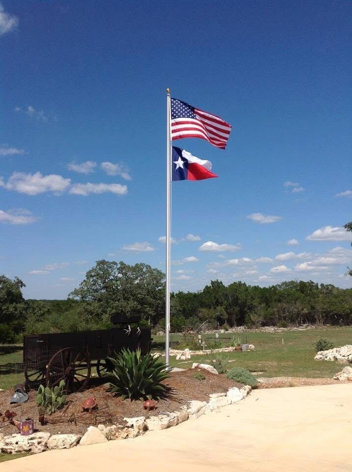 Residential flagpole flying U.S. and Texas flags at a Texas Hill Country home