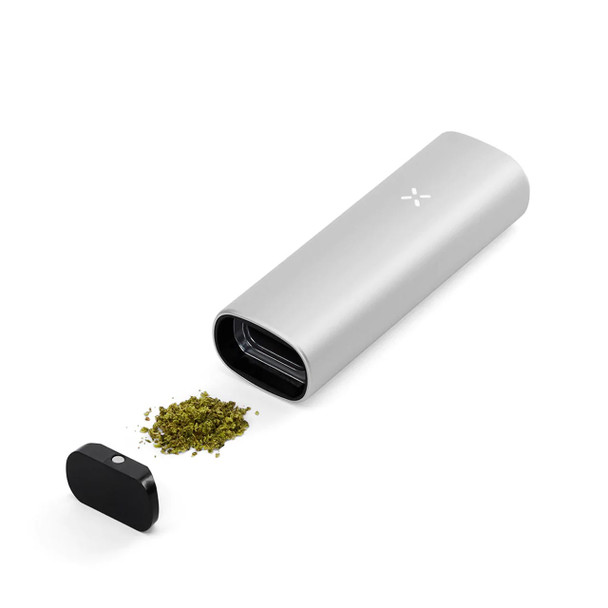 A Pax Mini Platinum with an open oven chamber and some ground flower spilled between the device and its oven lid.