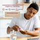 Man sitting at a desk taking a Geri-Care Cranberry 450mg tablet with a glass of water.