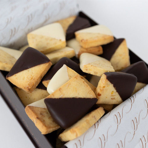 The picture features an assortment of bite-sized shortbreads elegantly presented in a box, showcasing their appealing design and textures.

In detail, the image displays a variety of small, rectangular shortbread that are partially coated in either dark chocolate or white chocolate. The shortbreads have a light golden-brown colour, indicating a buttery texture, and they appear to be freshly baked, with some showcasing a crumbly surface. The box containing the shortbreads is dark brown, adding a touch of sophistication, while a delicate patterned paper lining the inside enhances the presentation. The overall atmosphere is inviting and indulgent, evoking a sense of comfort and delight, likely appealing to anyone with a sweet tooth. The arrangement suggests a thoughtful gift or treat, making the scene feel festive and warm.