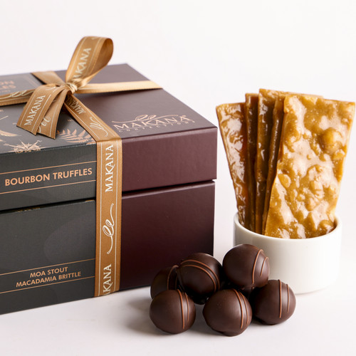 Makana Confections arrangement of handmade Bourbon Truffles and Moa Stout Brittle beside a ribboned stack of two luxurious brown product boxes.