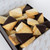 The picture features an assortment of bite-sized shortbreads elegantly presented in a box, showcasing their appealing design and textures.

In detail, the image displays a variety of small, rectangular shortbread that are partially coated in either dark chocolate or white chocolate. The shortbreads have a light golden-brown colour, indicating a buttery texture, and they appear to be freshly baked, with some showcasing a crumbly surface. The box containing the shortbreads is dark brown, adding a touch of sophistication, while a delicate patterned paper lining the inside enhances the presentation. The overall atmosphere is inviting and indulgent, evoking a sense of comfort and delight, likely appealing to anyone with a sweet tooth. The arrangement suggests a thoughtful gift or treat, making the scene feel festive and warm.