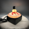 all Glass Melted version of the Classic glass snowman, featured with black top hat and red scarf. 4" round. Shown here glowing on a black square illuminating light base.