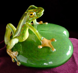 hand blown glass frog sculpture, with legs/arms, mirrored feet and added eye murrine, on hand sculpted  "lily pad" base, approx 4" round.  Body position, color and eyes will differ slightly as each is individually hand crafted, by Glass Artisan Chris Sherwin in his Bellows Falls glassblowing studio.