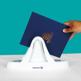 Hand placing a navy blue hard cover document with gold foil logo into the white UniBinder 60 thermal binding machine against a teal background.