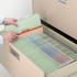 Gray-green top tab file folders organized in a filing cabinet drawer with labeled tabs and out guide