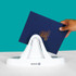 Hand placing a navy blue hard cover document with gold foil logo into the white UniBinder 60 thermal binding machine against a teal background.