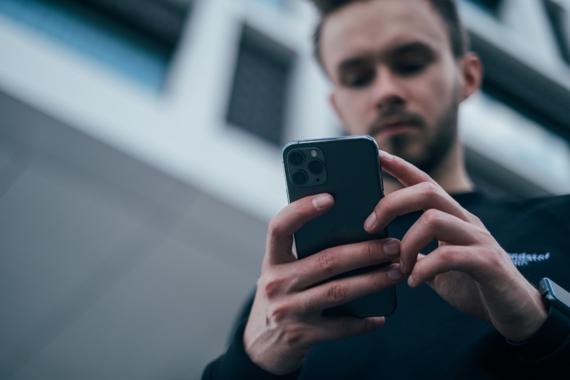 man wearing black sweater using a smartphone