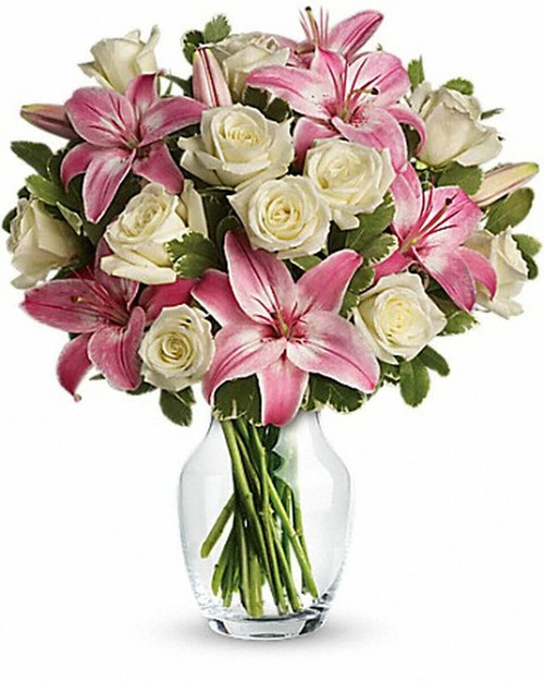 A romantic gift like this one is always appreciated. An eye-catching display of roses and lilies is perfectly arranged in a feminine vase which makes a beautiful and lasting impression.
Elegant white roses and sweet pink asiatic lilies are hand-arranged with greens. It's the perfect way to show you love her always and forever.