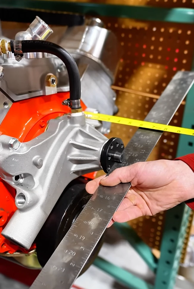 Measuring water pump height on an engine with a straight edge and tape measure