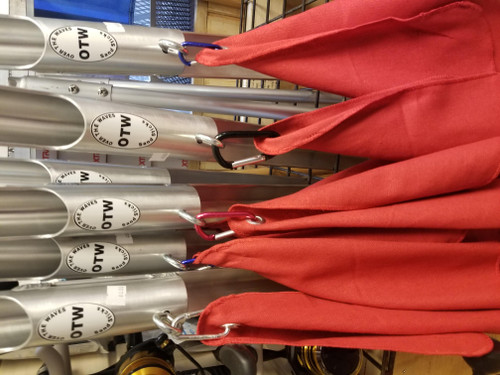 OTW Sand Sticks, red fabric sand shovels hanging on a display rack with metal poles.