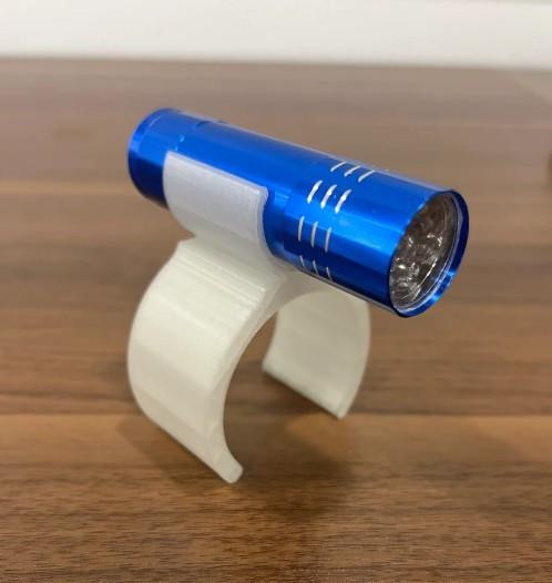 Reel Glo Sand Spike Reel Illuminator, compact blue flashlight mounted on a white adjustable holder placed on a wooden surface.