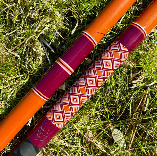Nick's Custom Rods 2026 Nick's Custom Rods - CTS 1305 Conventional, fishing rods with orange and purple patterns resting on grass.
