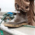 XTRATUF 22734 Ankle Deck Boot, close-up of a black rubber ankle deck boot worn on a person's foot, standing on a boat with a coiled rope nearby.