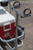 ANGLER'S FISH-N-MATE Fish-N-Mate 587 Beach Chair holder, a sturdy metal stand with dual cup holders and secure grips for holding beach chairs, placed on sandy ground next to a cooler.