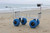 ANGLER'S FISH-N-MATE Fish-N-Mate 839 4 Wheel Cart, a sturdy and functional fishing cart with large blue wheels and a metal frame designed for outdoor use, placed on a sandy beach near the ocean.