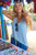 HUK WAYPOINT FLOW TANK, woman smiling and wearing a light blue tank top at a beach market.