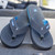 FROGG TOGGS Frogg Toggs Men's Flipped Out Sandal, a pair of grey and blue flip-flop style sandals with textured soles and adjustable straps placed outdoors on a surface.