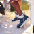 XTRATUF XADSW109 Women's Ankle Deck Boot, close-up of blue waterproof ankle boot on sandy surface with a person wearing it in outdoor setting.