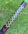 Nick's Custom Rods 2025, close-up of a fishing rod handle with a vibrant, geometric pattern in green, black, and purple colors.