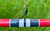 Nick's Custom Rods 2025 Nick's Custom Rods - CTS 1305, close-up of a fishing rod guide and wrapping, red rod with black, white, and red decorative wraps against grassy background.