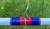 Nick's Custom Rods 2025, close-up of a fishing rod with a white, blue, and red eyelet guide on a green grassy background.