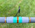 Nick's Custom Rods 2025 Nick's Custom Rods - CTS 1305, a close-up image of a fishing rod with a colorful wrapped section and a black metal guide ring against a grassy background.