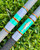 NICK'S CUSTOM RODS 2025 Nick's Custom Rods - CTS 1305, a fishing rod with colorful striped design and a fish graphic, resting on green grass.