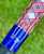 Nick's Custom Rods 2025 Nick's Custom Rods - CTS 1305, close-up of a fishing rod with red, white, blue, and gold intricate design and logo on a blue section.