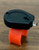 Reel Glo Reel Glo Reel Illuminator, small black device with an orange attachment, placed on a wooden surface.