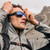 NATIVE Native Badlands Polarized Sunglasses, a man wearing sporty sunglasses with a mountain landscape background.