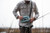 TOADFISH Waterproof Tote & Sling, a person holding the waterproof bag while fishing outdoors in a marshy area.