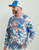 HUK Icon KC Printed LS Crew, male model wearing a blue and white camouflage patterned long-sleeve shirt with orange HUK logo and text, paired with a blue and white trucker cap.