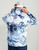 HUK Pursuit Mossy Oak Printed Hoodie, man wearing a white, blue, and black camouflage printed hoodie with hood, with the text 'HUK FISHING' on the back.